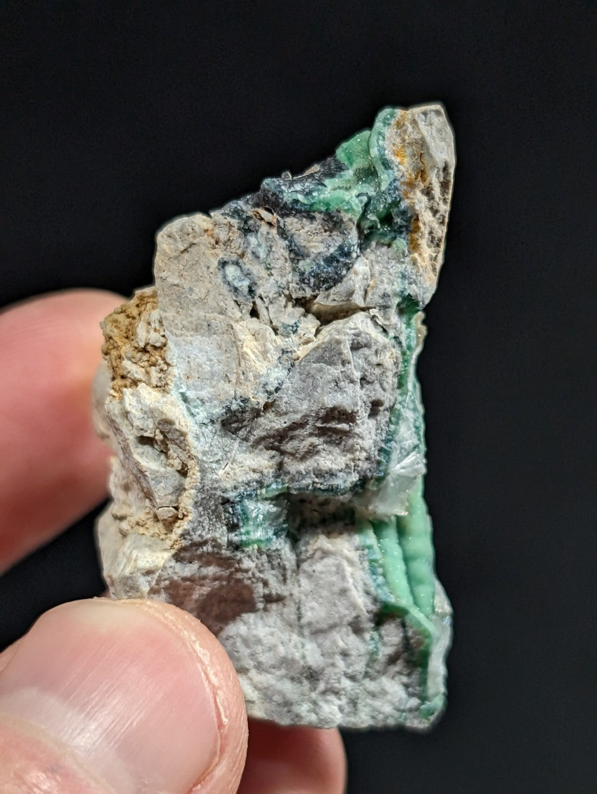 A rough, irregularly shaped piece of malachite mineral with vibrant green patches set against a mottled gray and white matrix.