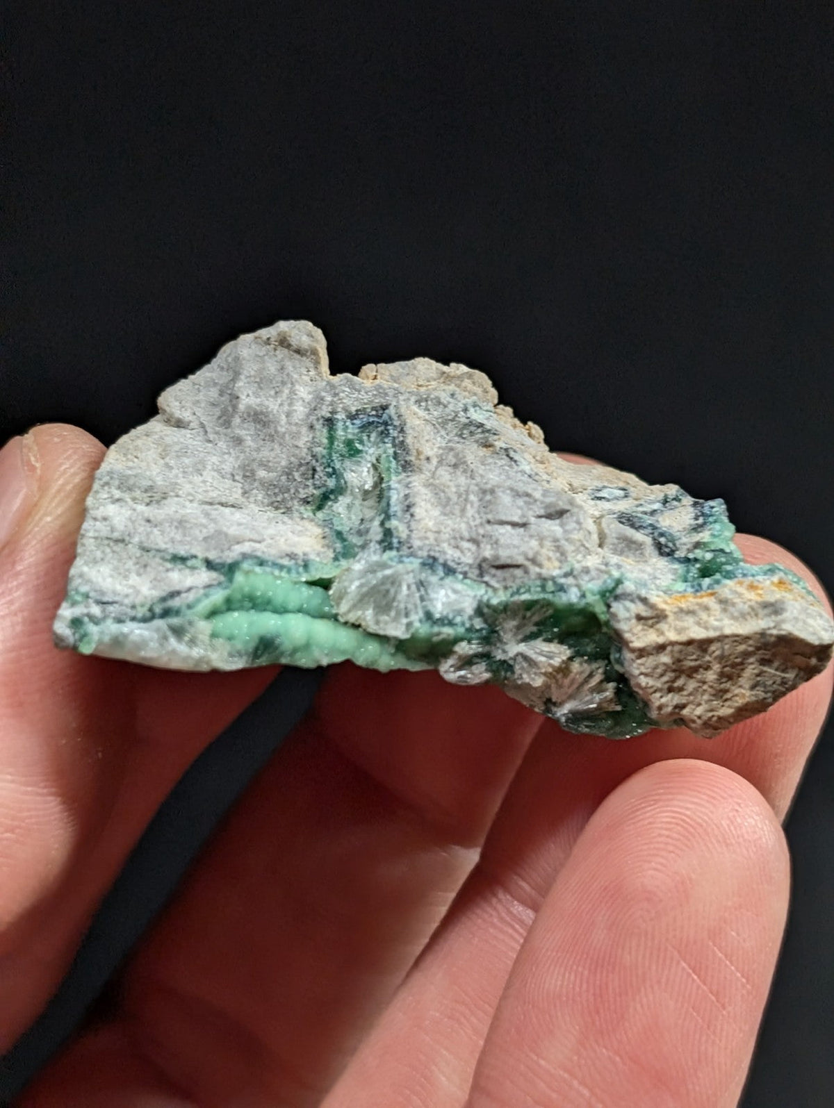 A rough, irregularly shaped piece of green and gray mineral with visible crystalline formations.