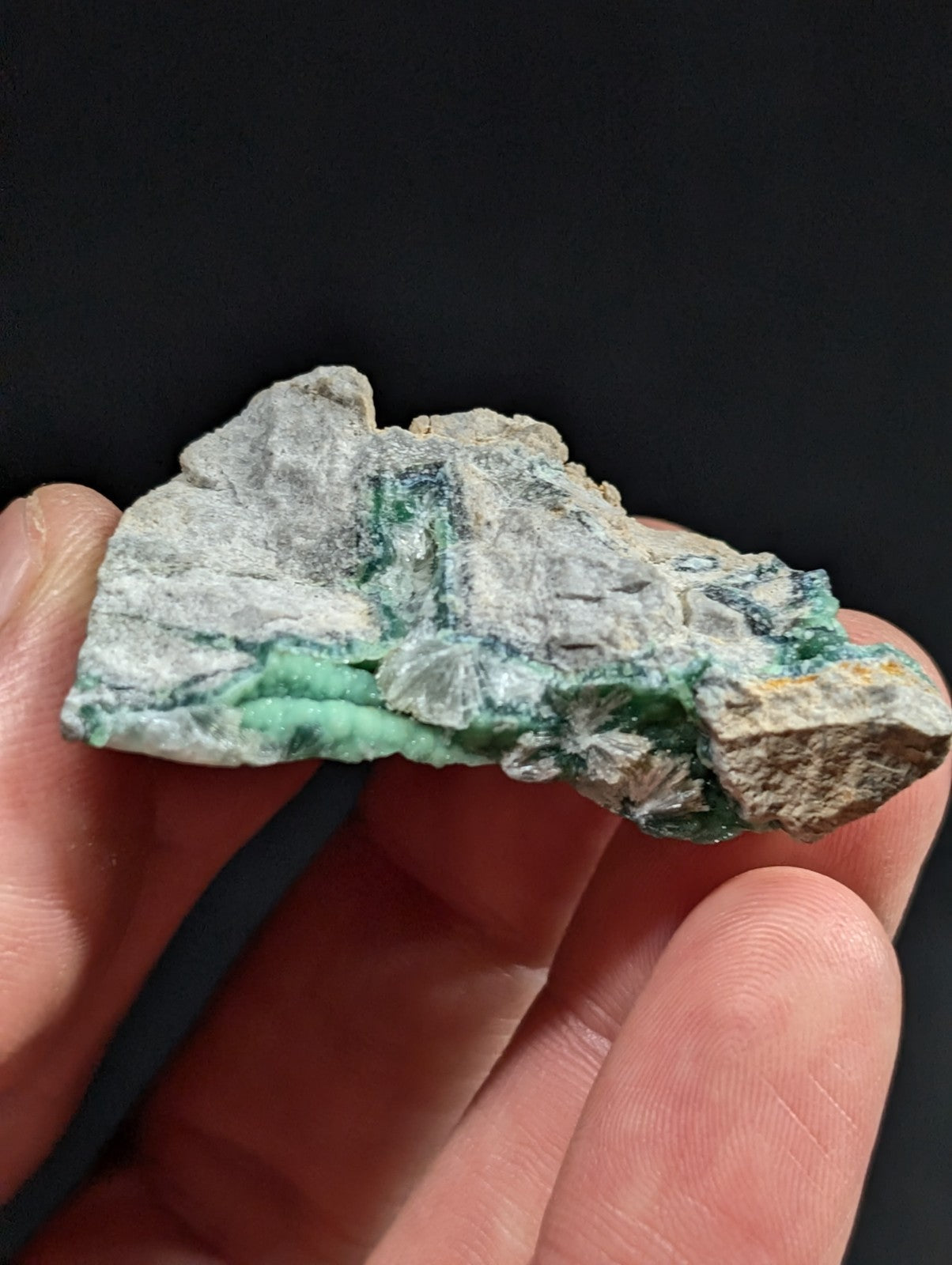 A rough, irregularly shaped piece of green and gray mineral with visible crystalline formations.