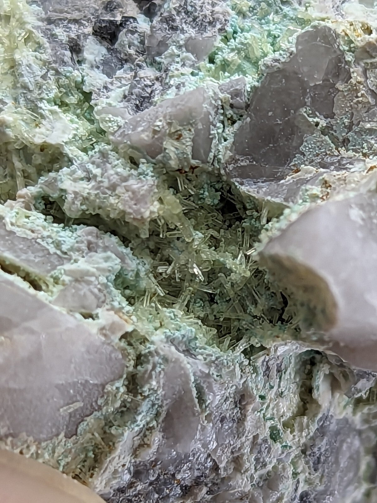 A cluster of translucent green and gray mineral crystals with a rough, jagged texture.