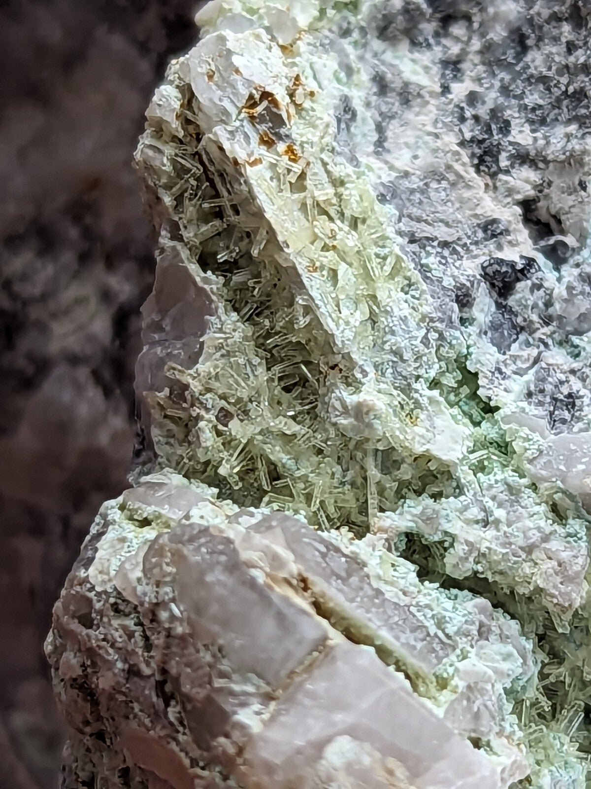 A cluster of translucent, pale green crystals growing from a rougher gray rock matrix.