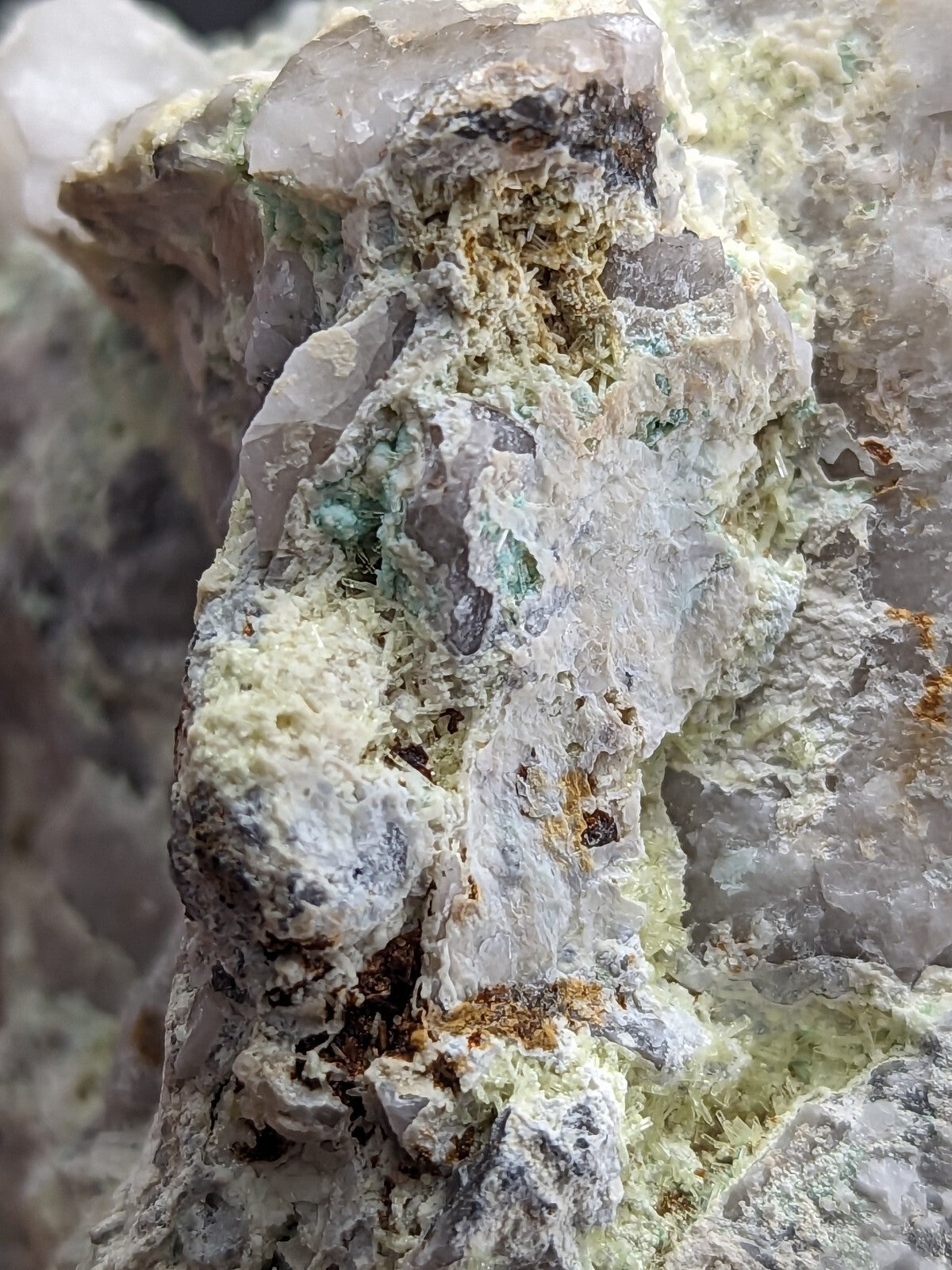 A rugged, translucent quartz specimen with embedded green and brown mineral inclusions.