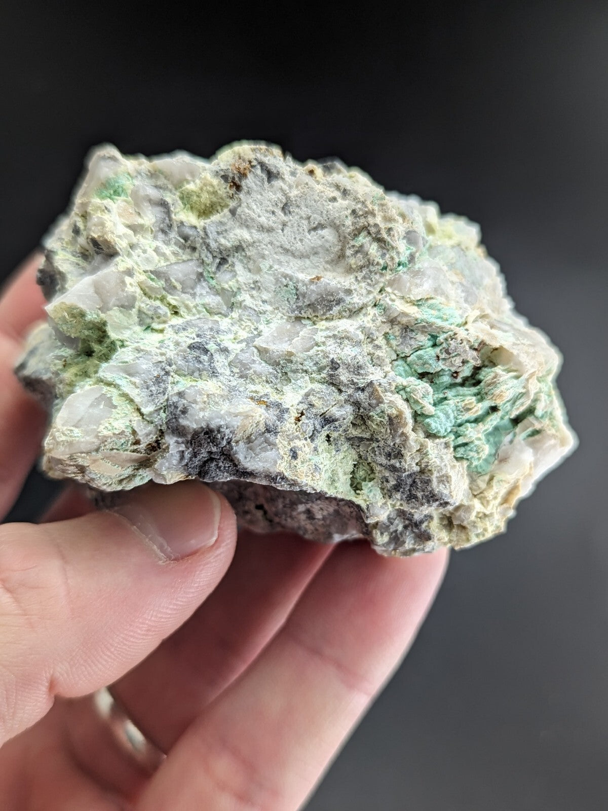 A rough, irregularly shaped mineral specimen with a mottled surface of pale green and grayish-white patches.