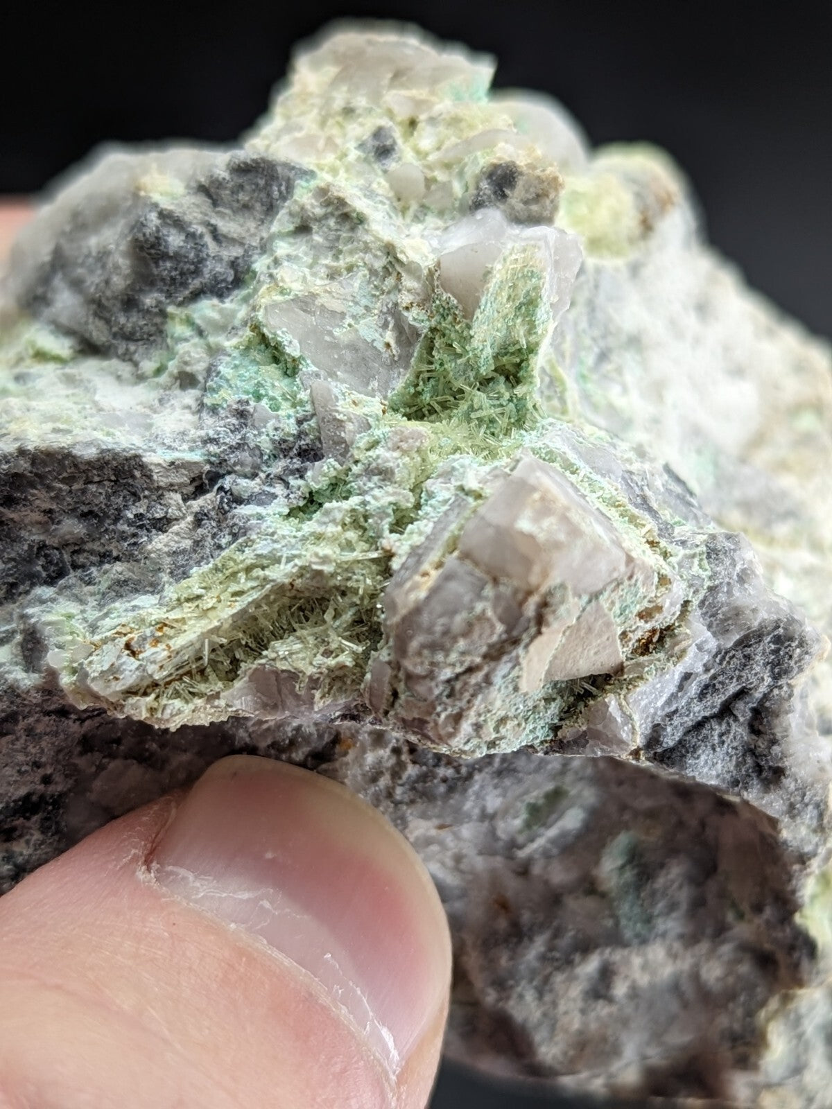 A rough, irregularly shaped mineral specimen featuring translucent quartz crystals embedded in a matrix of dark gray rock and vibrant green moss-like veining.