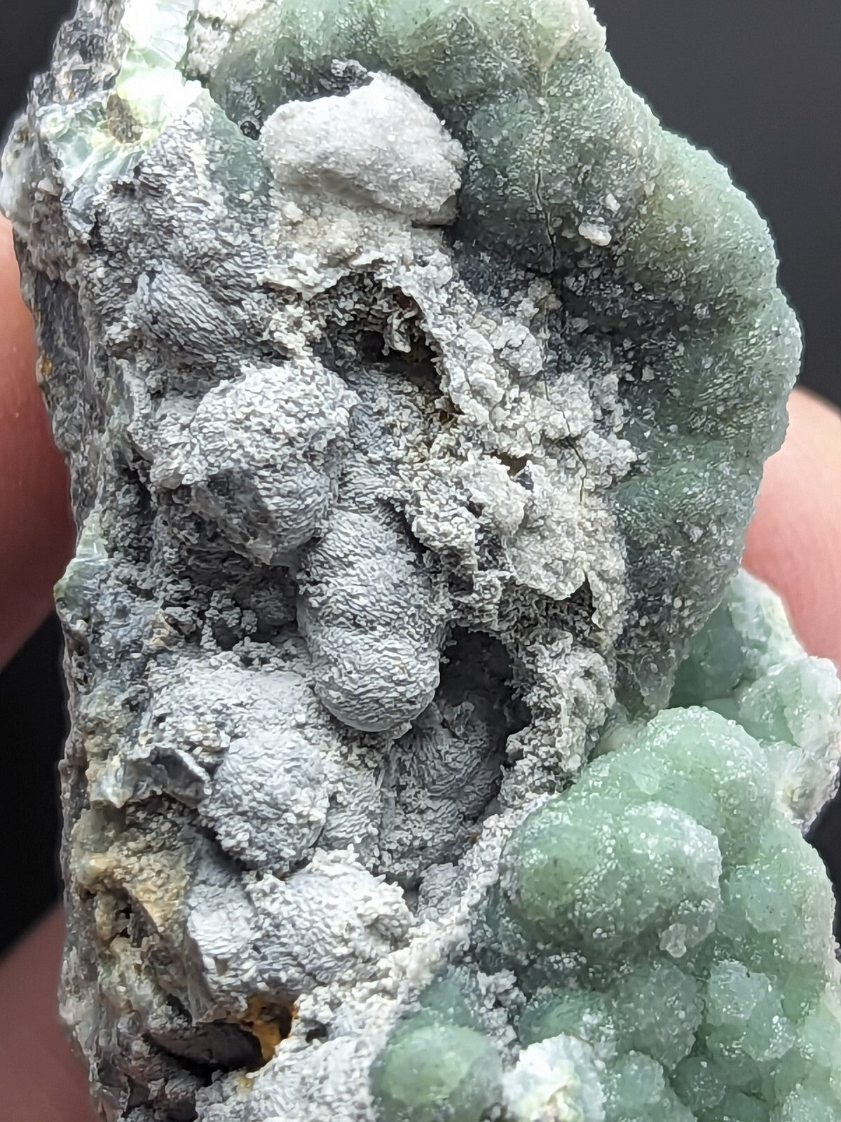 A textured green and gray mineral specimen with crystalline formations.