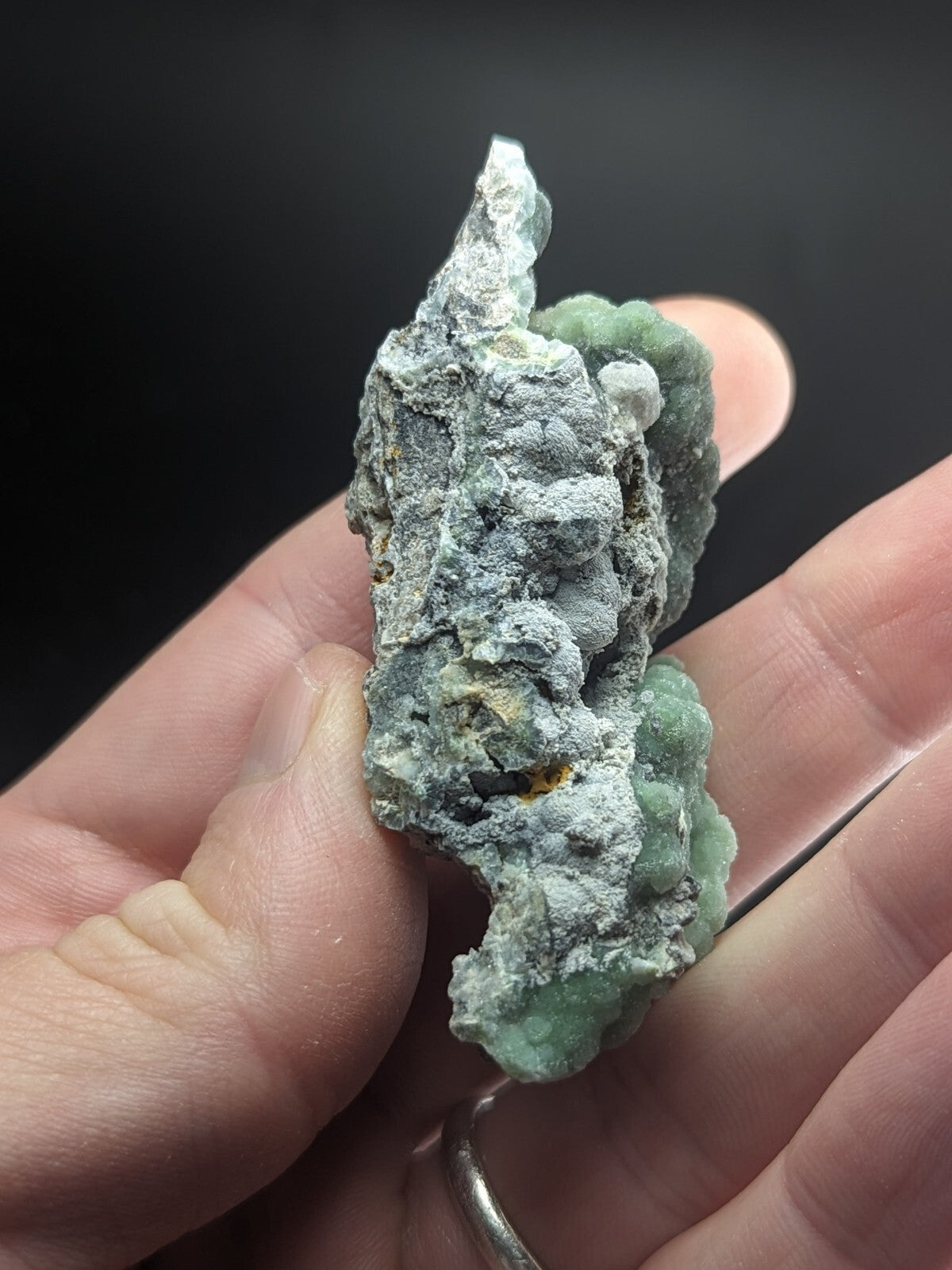 A textured, irregularly shaped mineral specimen with a mottled green and gray surface.