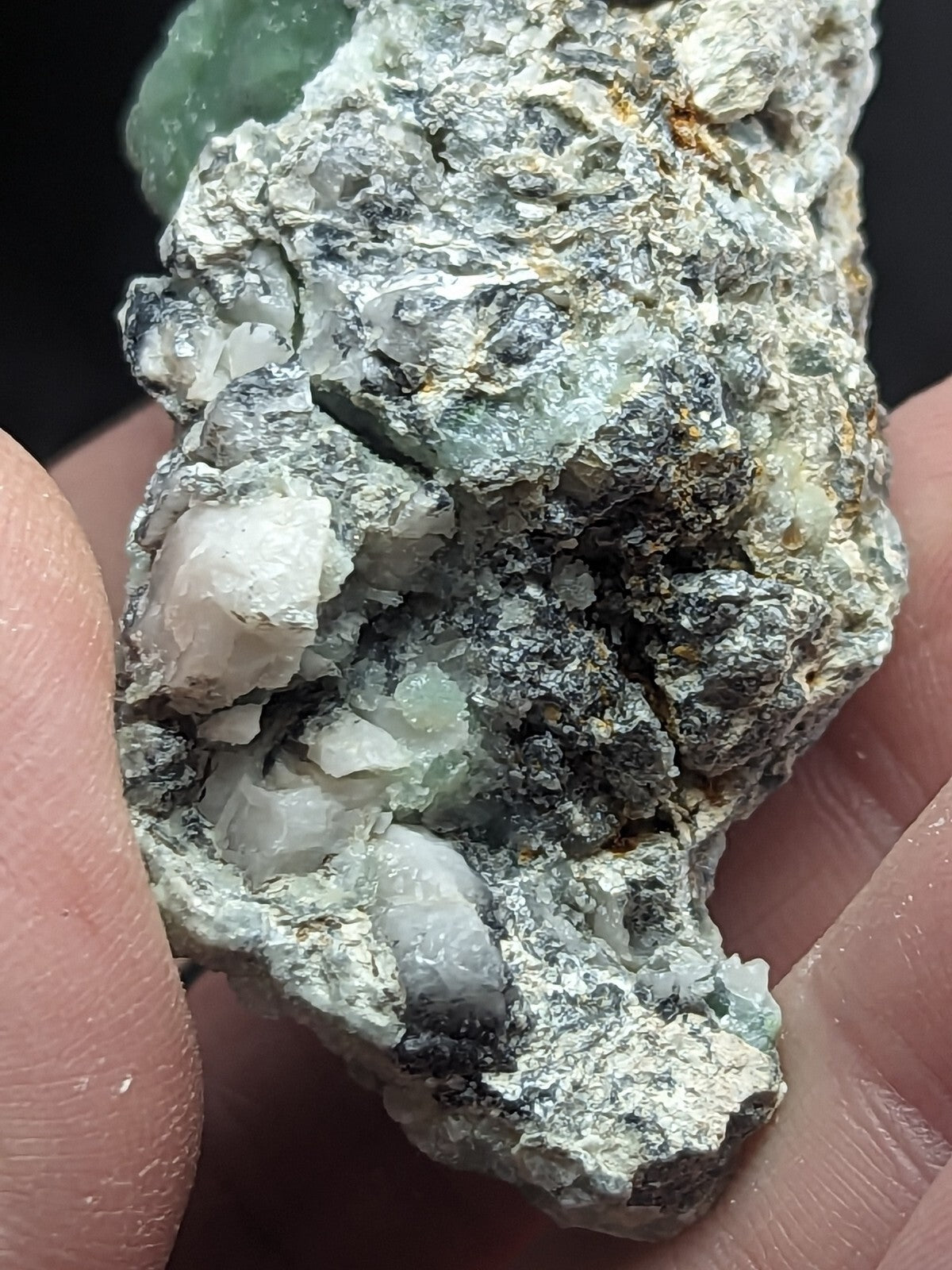 A rough, irregularly shaped mineral specimen with a mix of translucent green and white crystalline formations embedded in a grayish matrix.