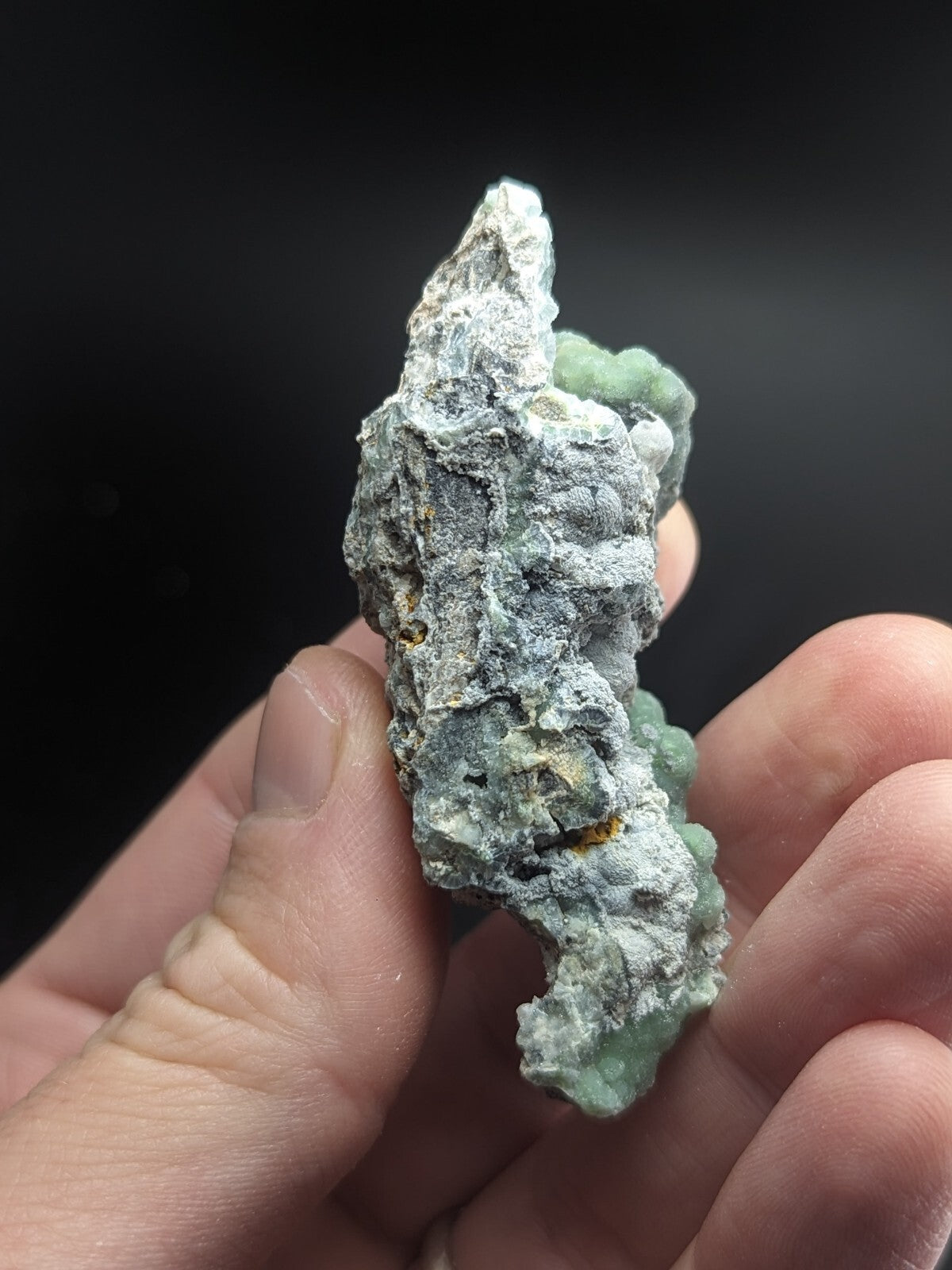 A rough, irregularly shaped mineral specimen with a mottled gray and pale green surface.