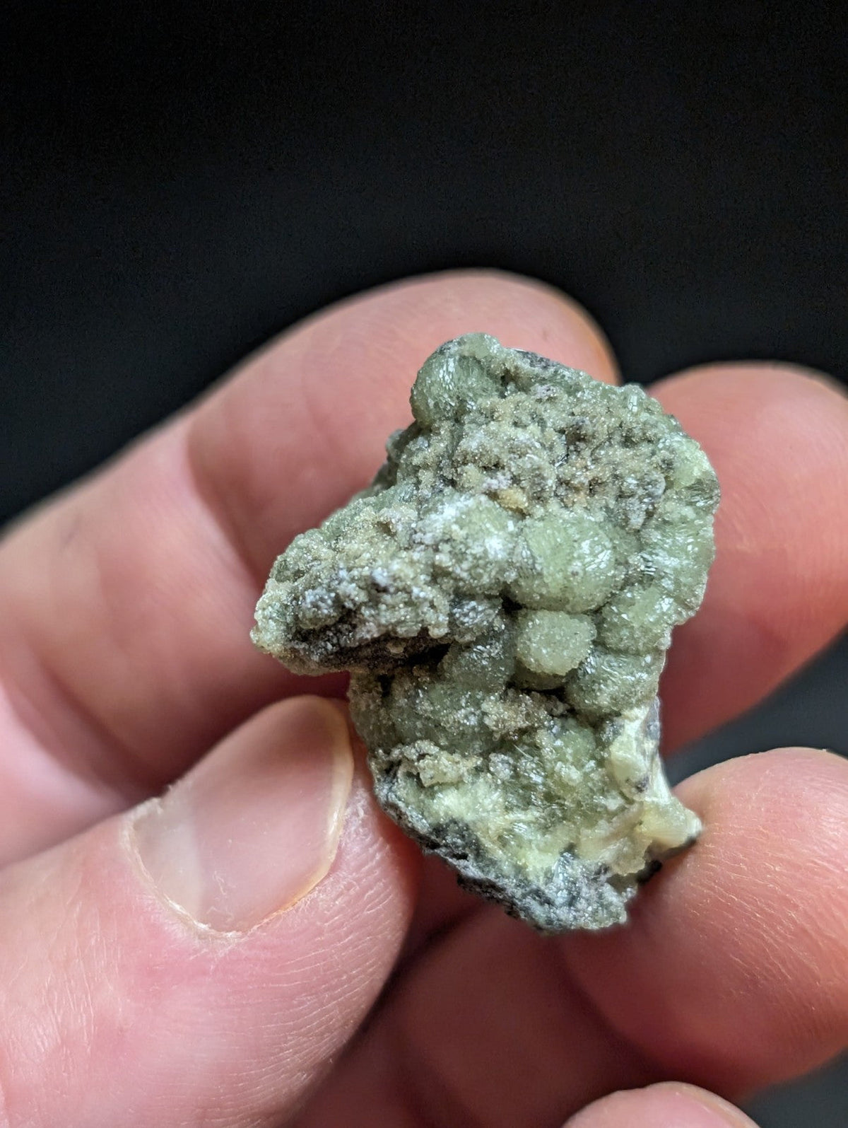 A textured, pale green mineral specimen with rounded nodules and a rough surface.