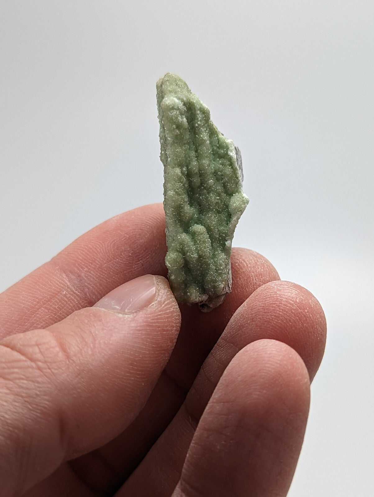 A textured, light green mineral specimen with a rough, crystalline surface.