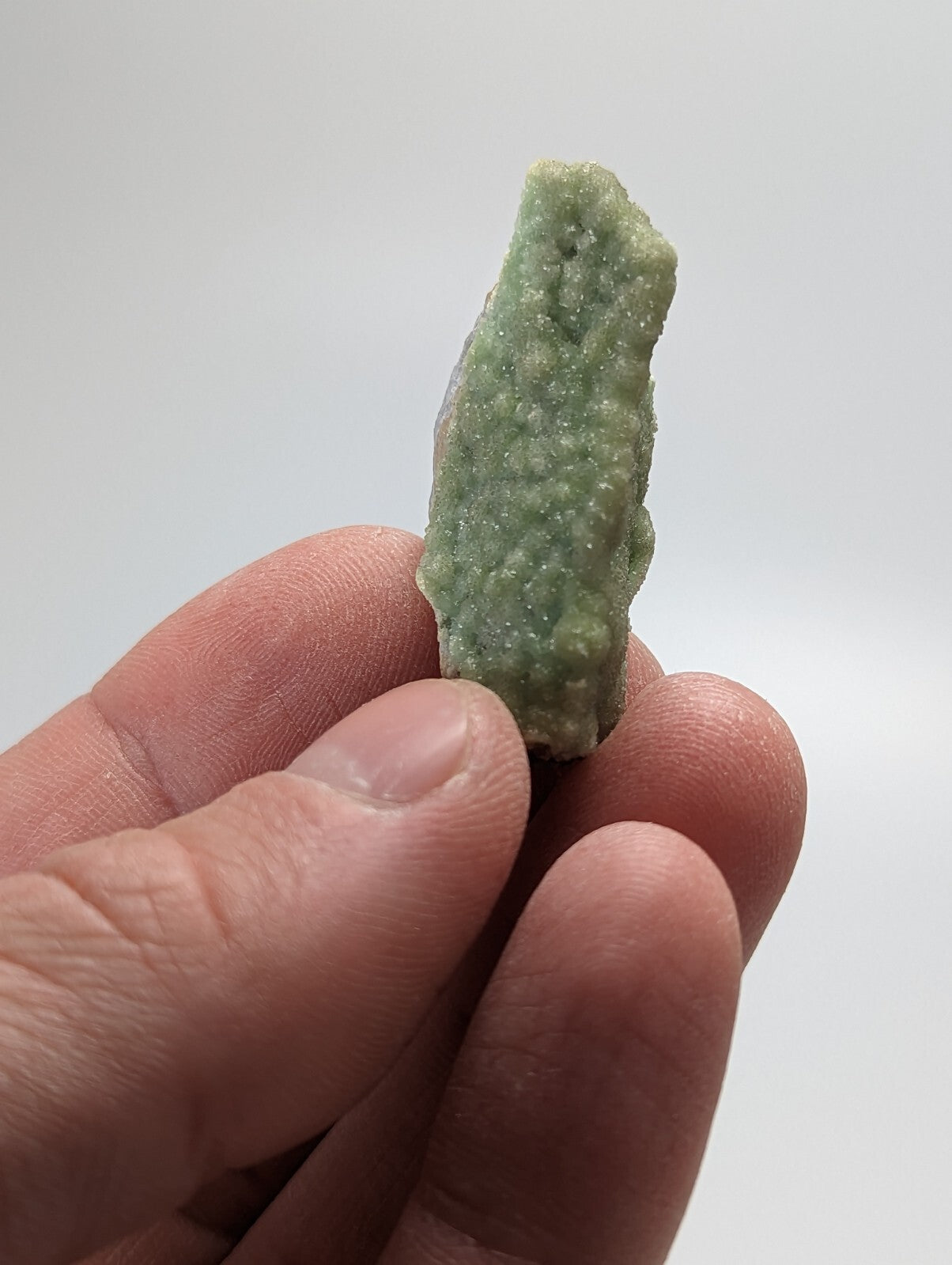 A pale green, rough-textured mineral specimen with a bumpy surface.