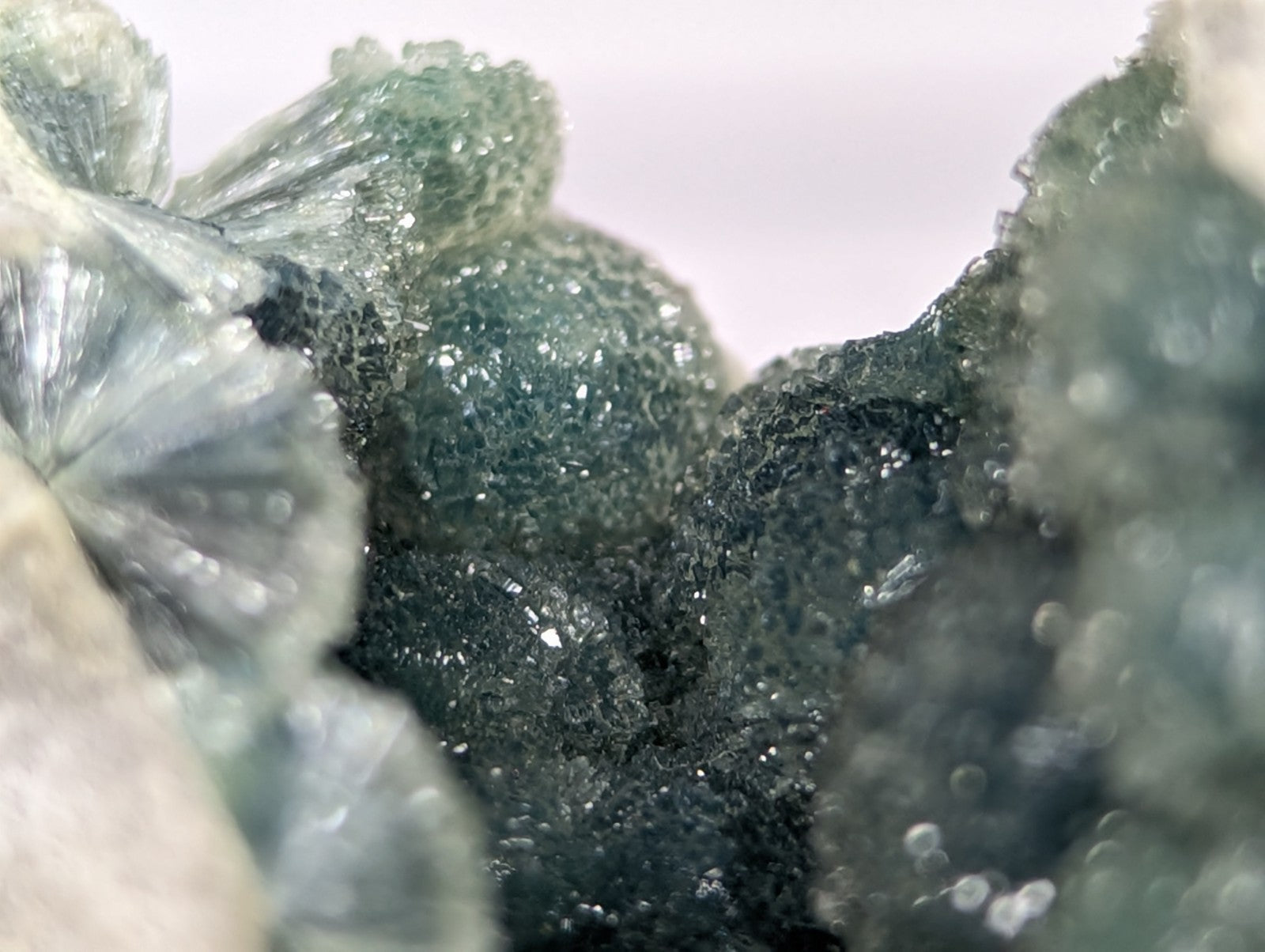 A cluster of translucent green and dark gray mineral crystals with a rough, textured surface.