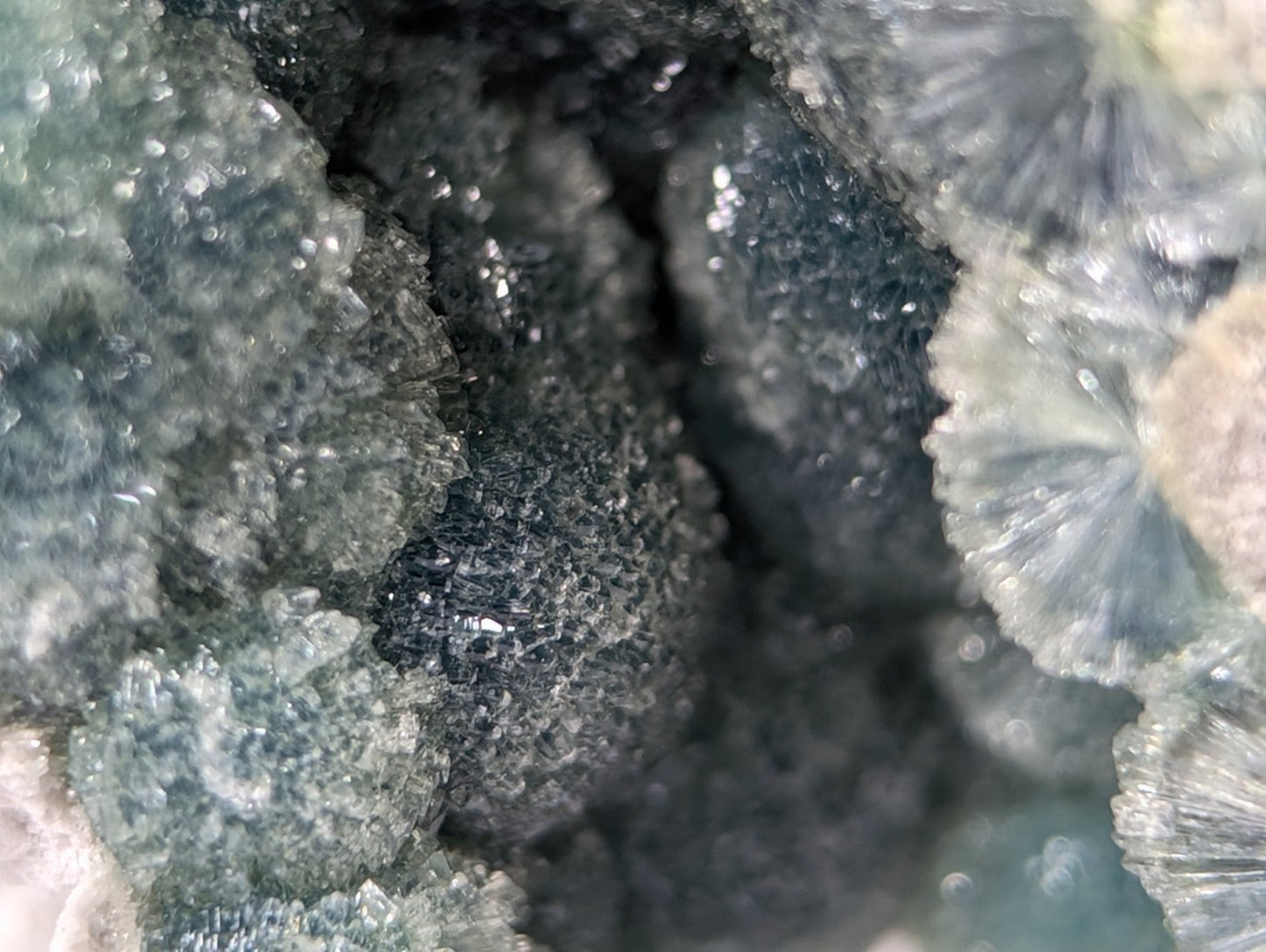 A dark, textured mineral specimen with translucent greenish-blue crystalline formations.