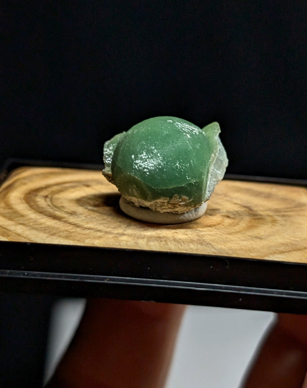A polished, translucent green jade stone with a smooth, rounded surface and natural crystalline edges.