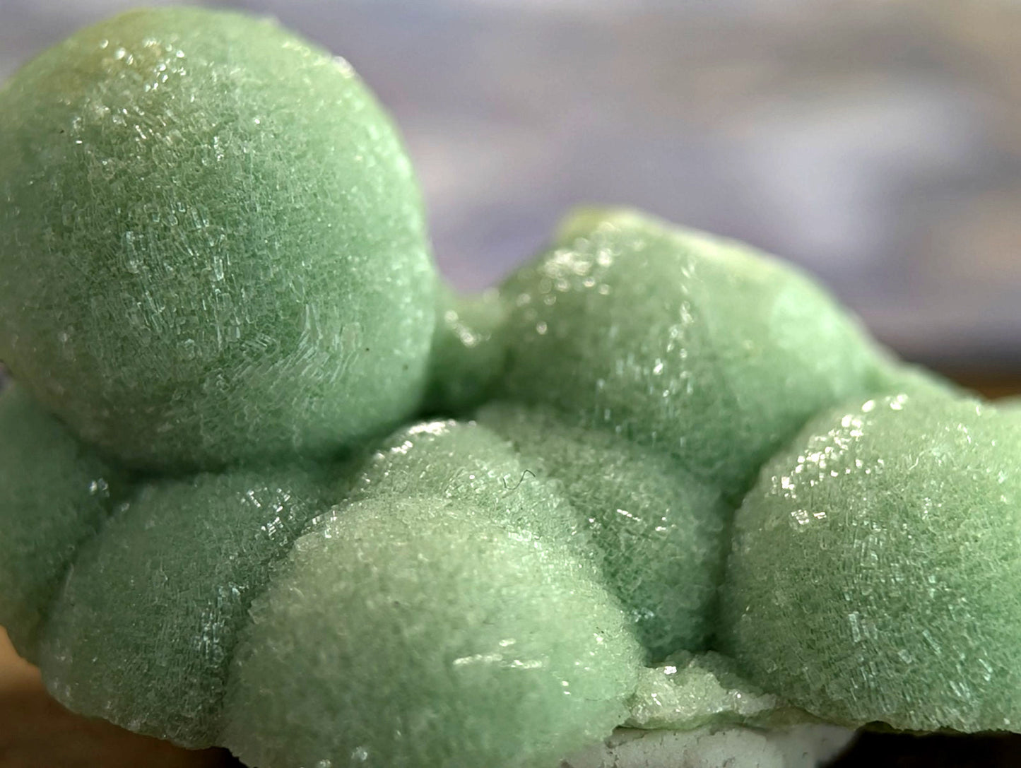 A cluster of translucent, light green crystalline formations with a textured, frosty surface.