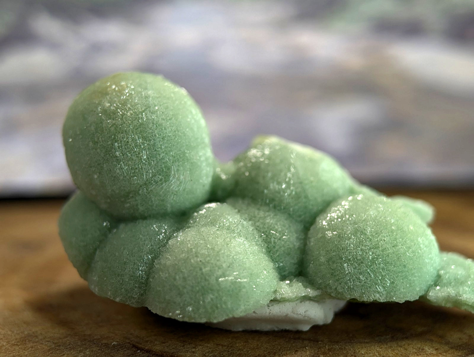 A pale green, textured mineral specimen with rounded, bubble-like formations and a crystalline surface.