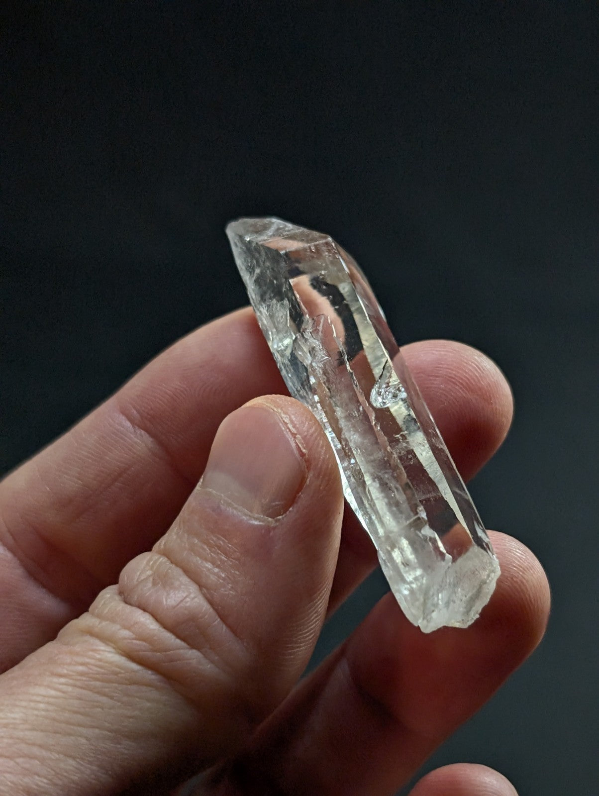 A clear, transparent quartz crystal with a pointed tip and natural facets.