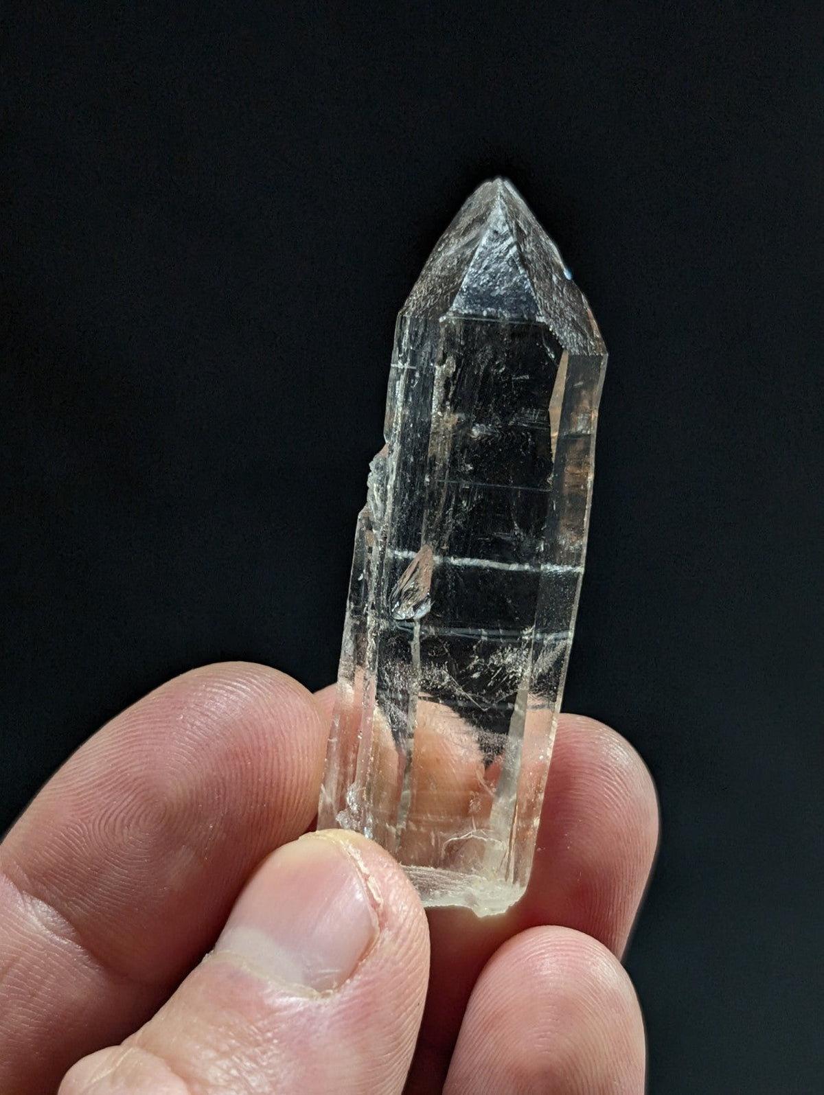 A clear, translucent quartz crystal with a pointed tip and visible internal striations.