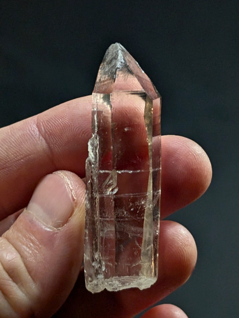 A clear, transparent quartz crystal with a pointed top and natural facets.