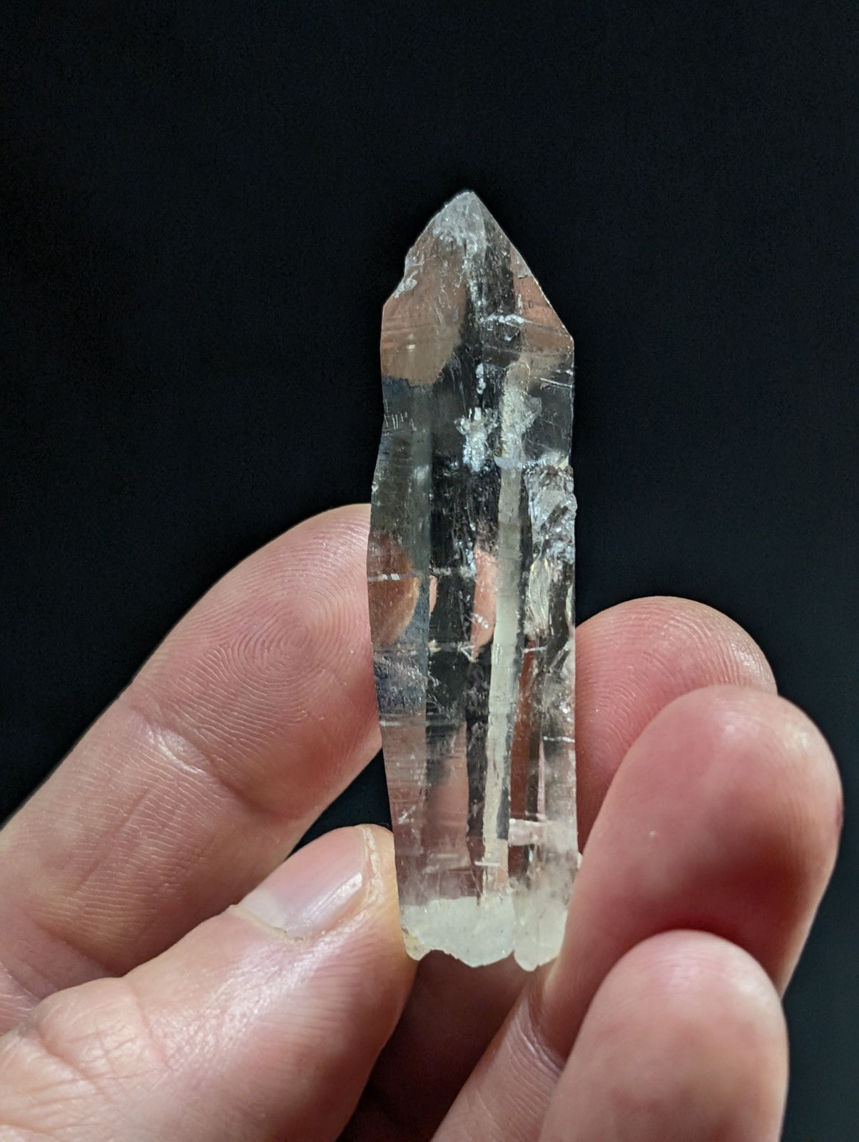 A clear, translucent quartz crystal with a pointed tip and natural internal striations.