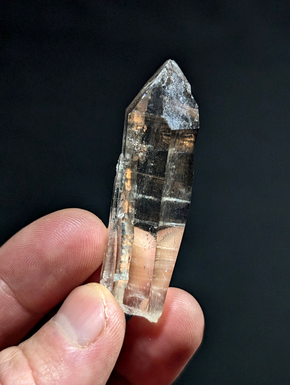 A translucent, clear quartz crystal with a pointed tip and visible internal striations.