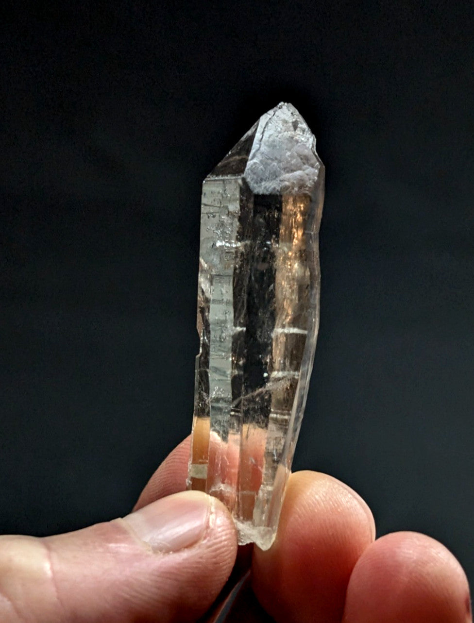 A clear, translucent quartz crystal with a pointed tip and visible internal striations.