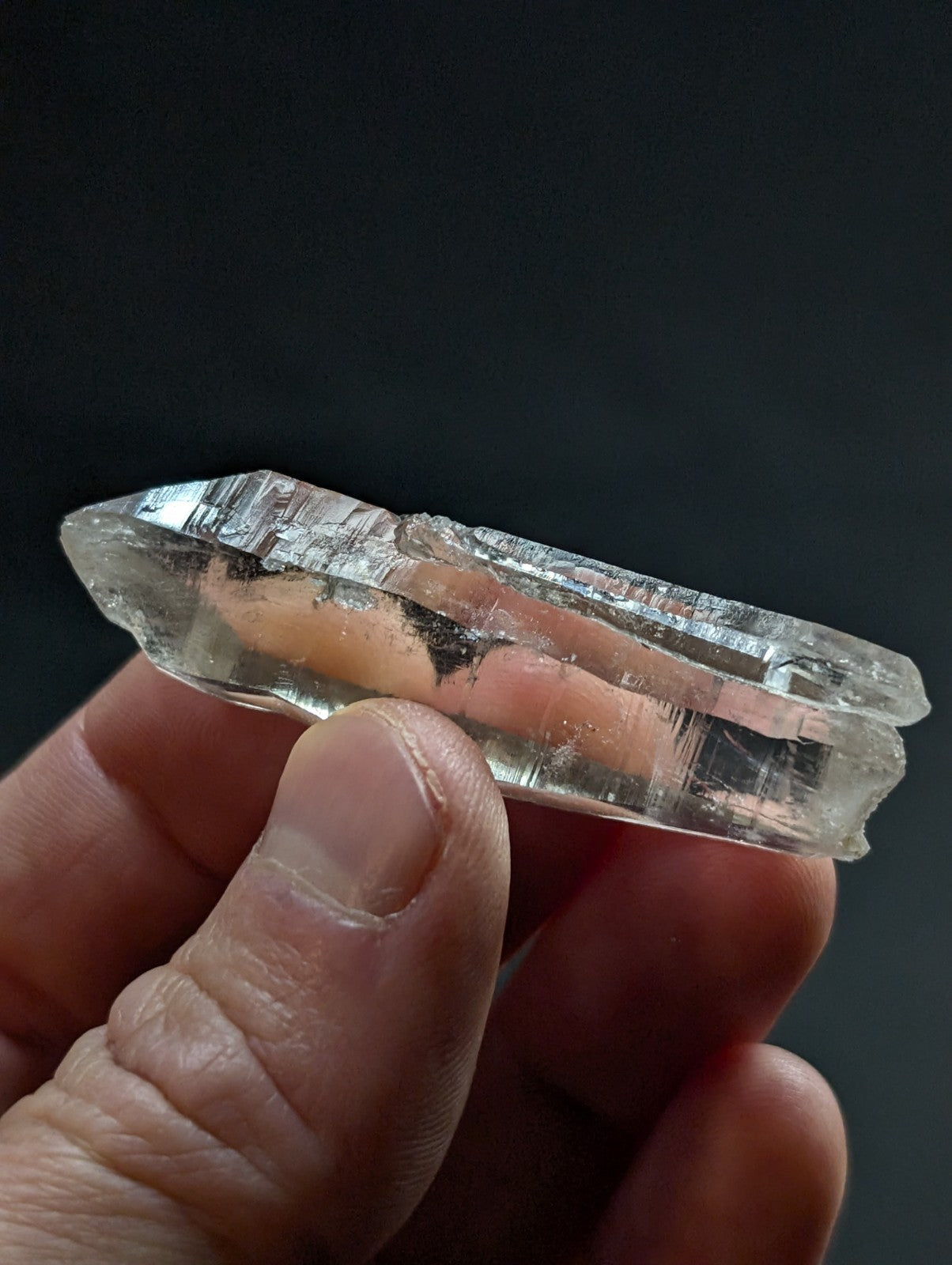A translucent, clear quartz crystal with natural striations and a pointed tip.