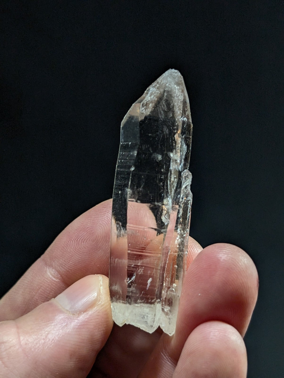 A translucent, clear quartz crystal with a pointed tip and natural facets.