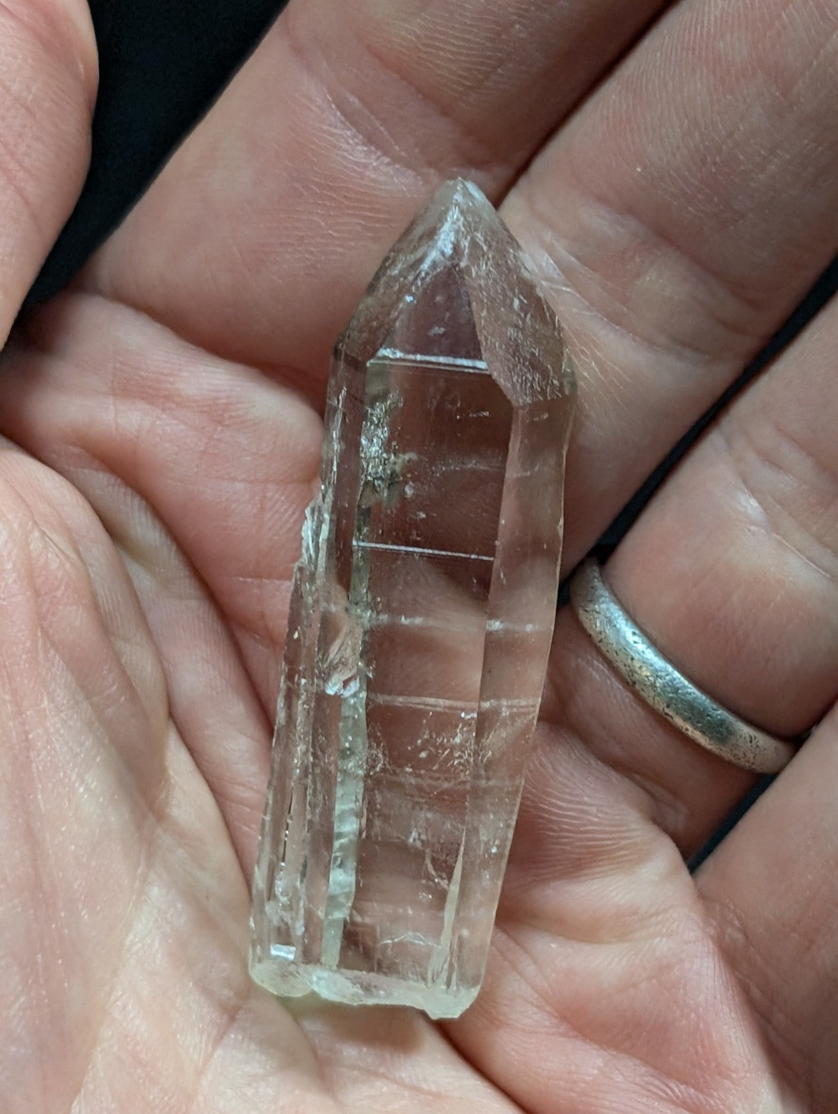 A clear, translucent quartz crystal with a pointed tip and natural facets.
