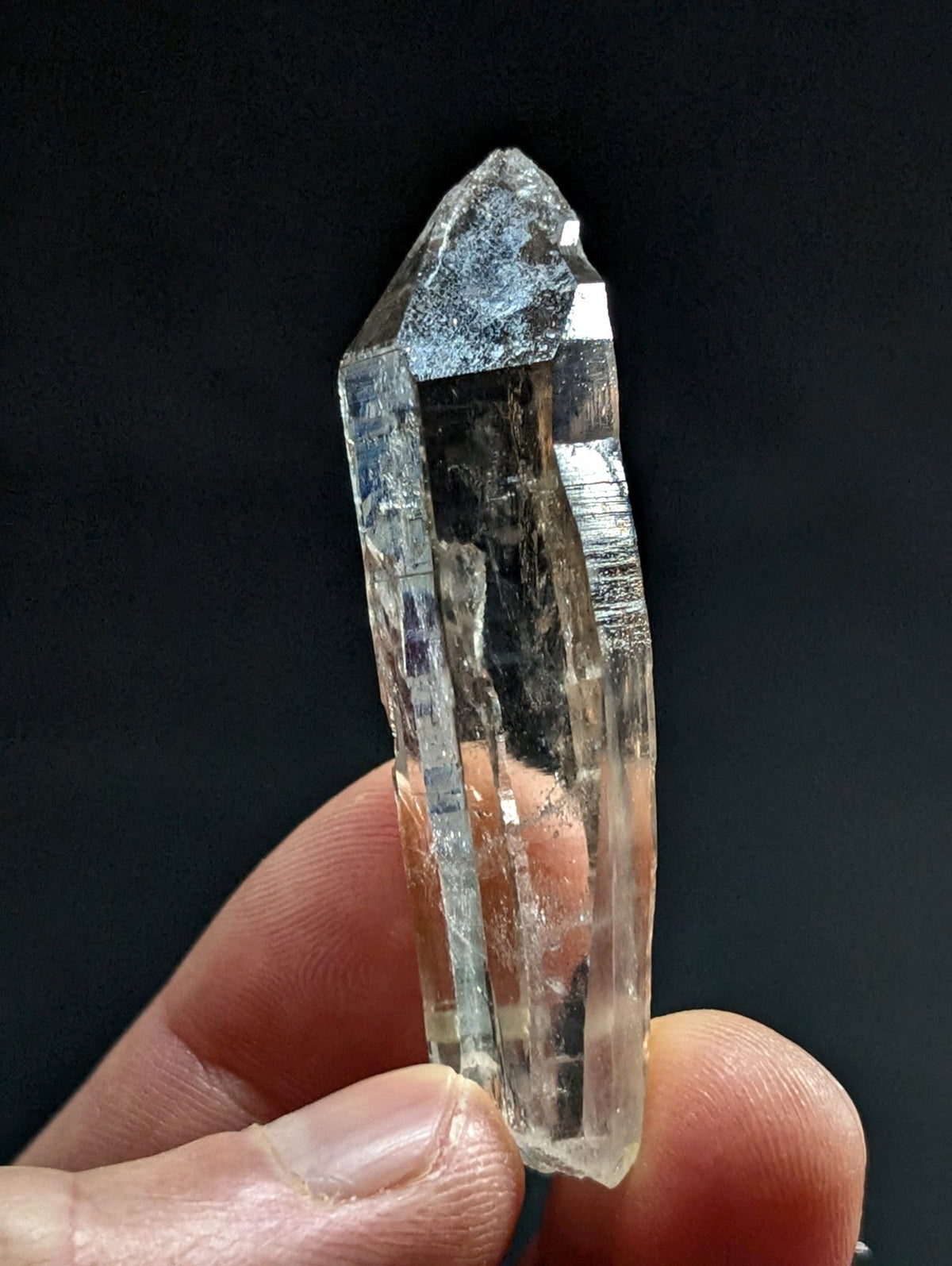A translucent, clear quartz crystal with a pointed tip and visible internal striations.