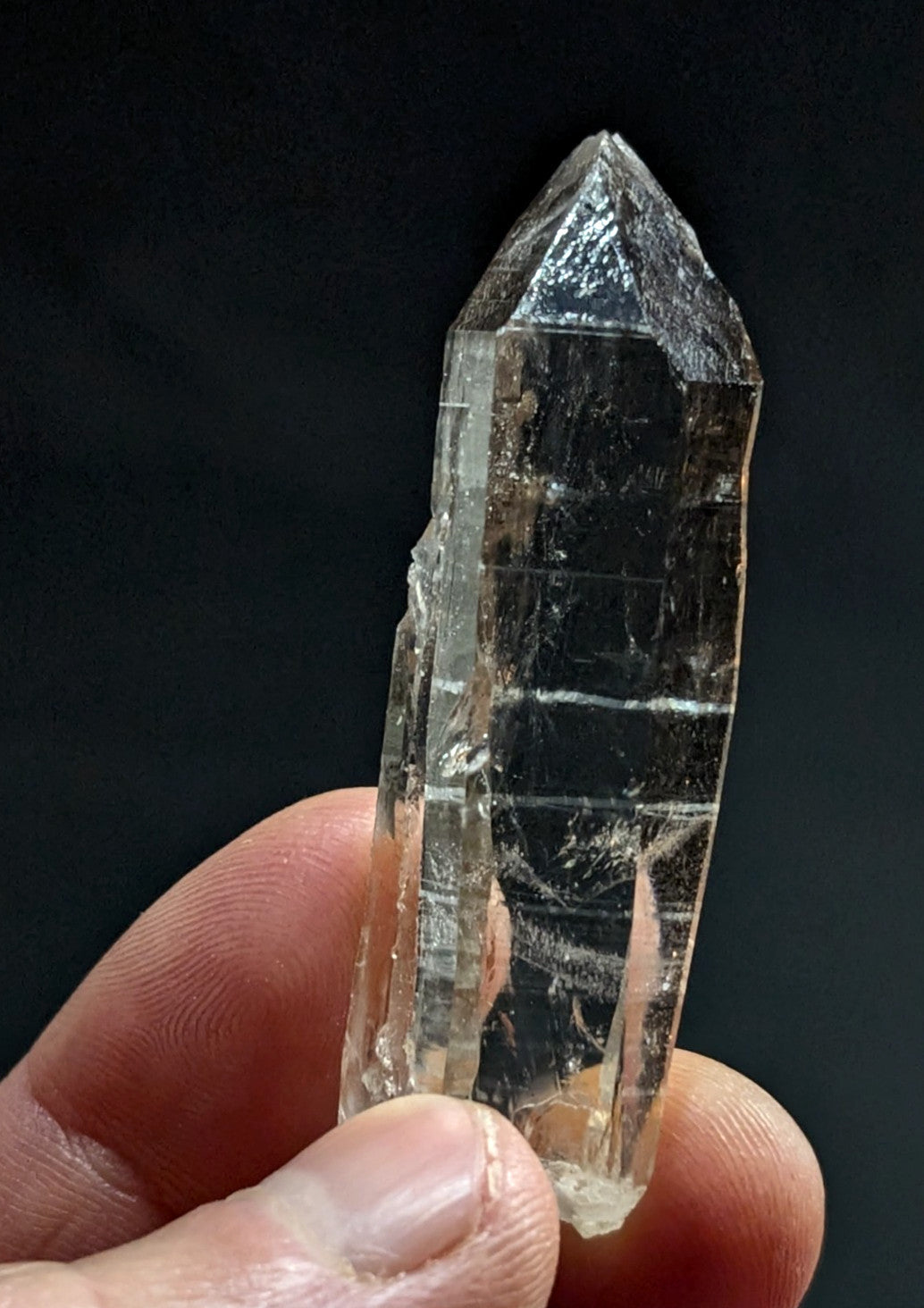 A translucent, clear quartz crystal with a pointed tip and visible internal striations.