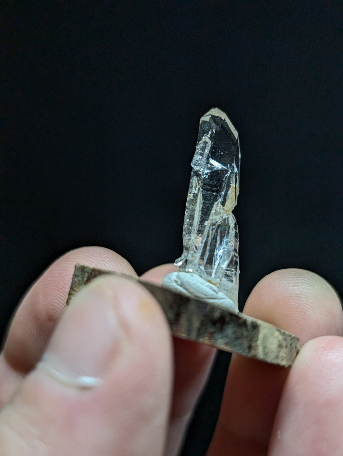 A clear, transparent quartz crystal with a pointed tip and visible internal facets.