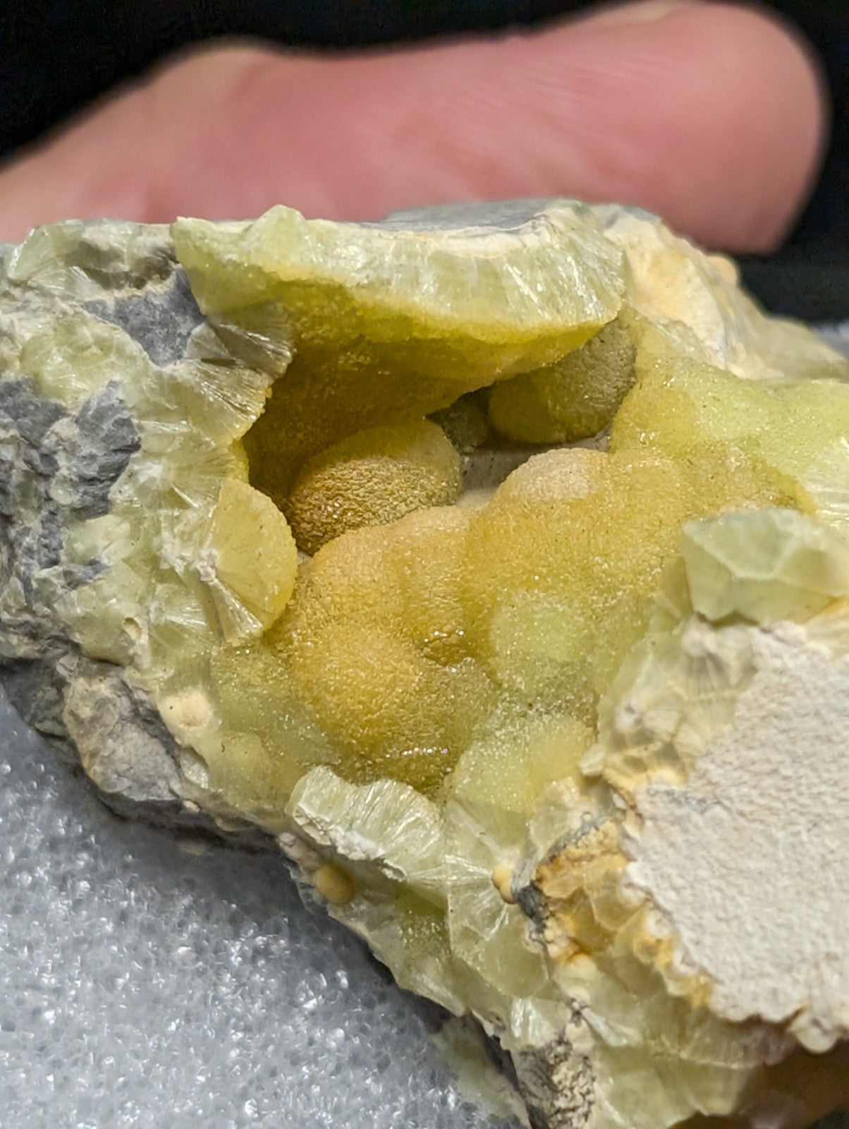 A vibrant yellow-green fluorite geode with a textured, crystalline interior and grayish matrix exterior.